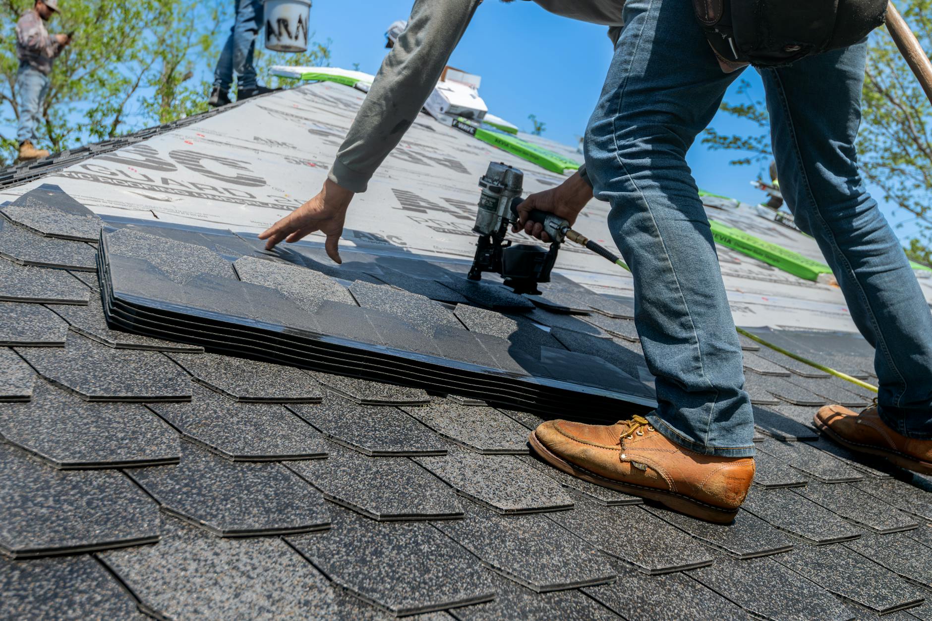 A professional roofer wearing safety gear inspecting a residential roof deck in Stayton, Oregon.